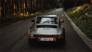 道路を走るシルバーの車の写真。