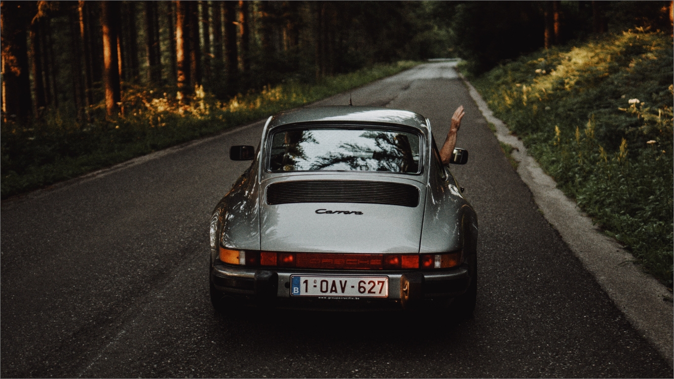 道路を走るシルバーの車の写真。